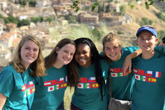 A small group of students wearing matching tee shirts showing various flags from different countries.